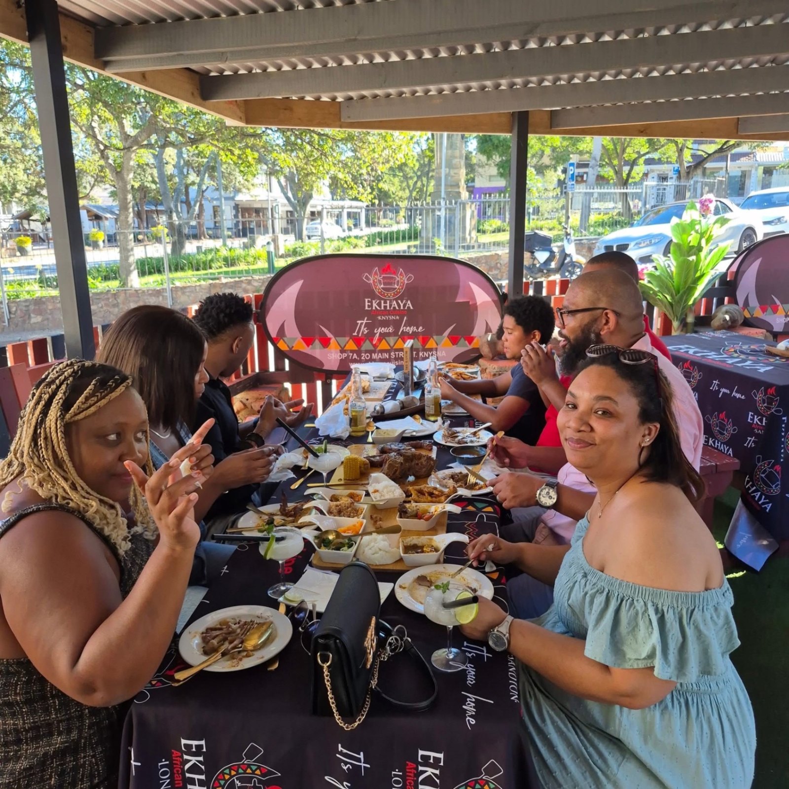 A South African family sharing pap, chakalaka and grilled meat around a table at sunset